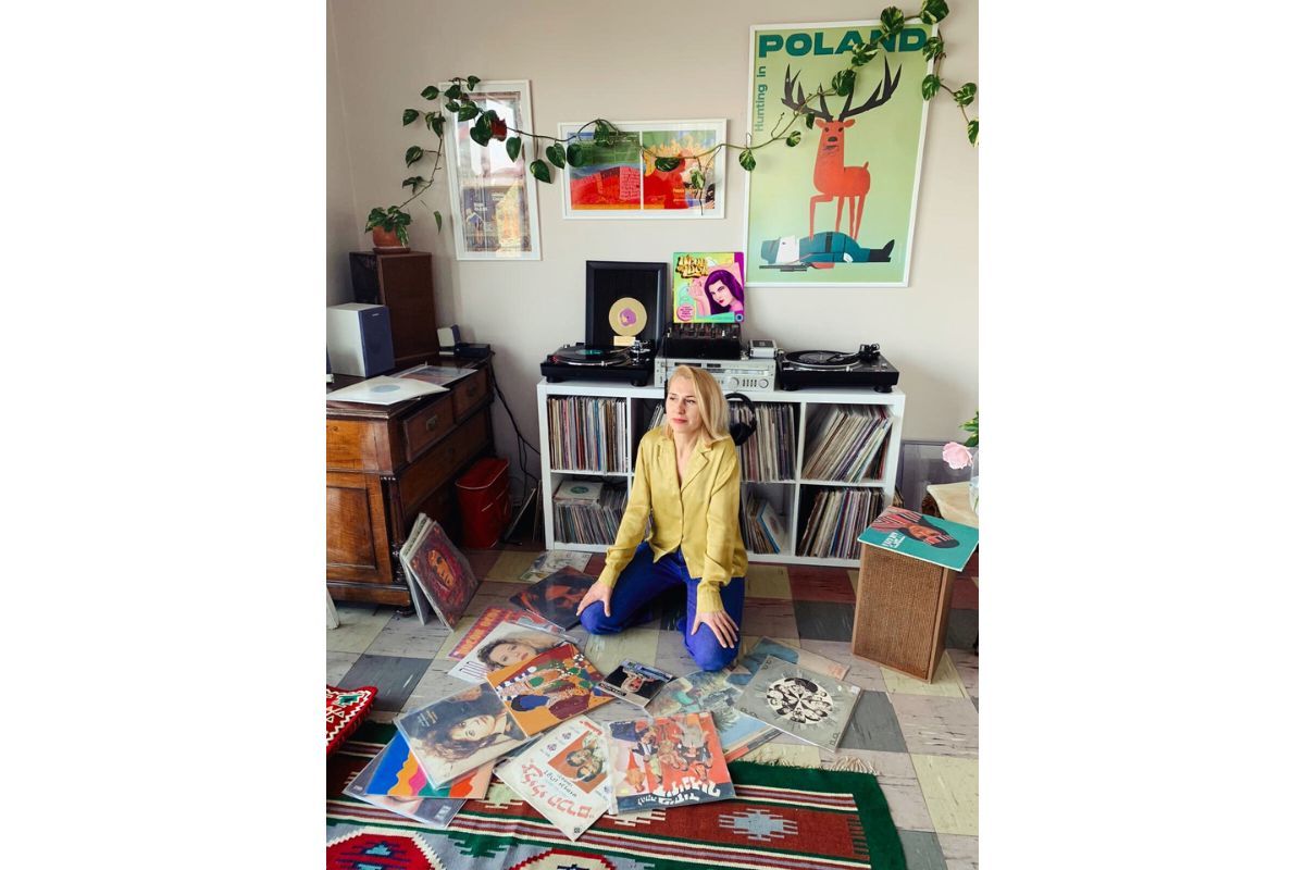 Kornelia kneels on the floor, surrounded by records