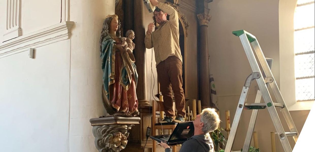 Two men scanning a mounted statue of the Madonna and child