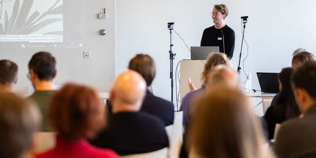 An audience looking at speaker stood on a podium