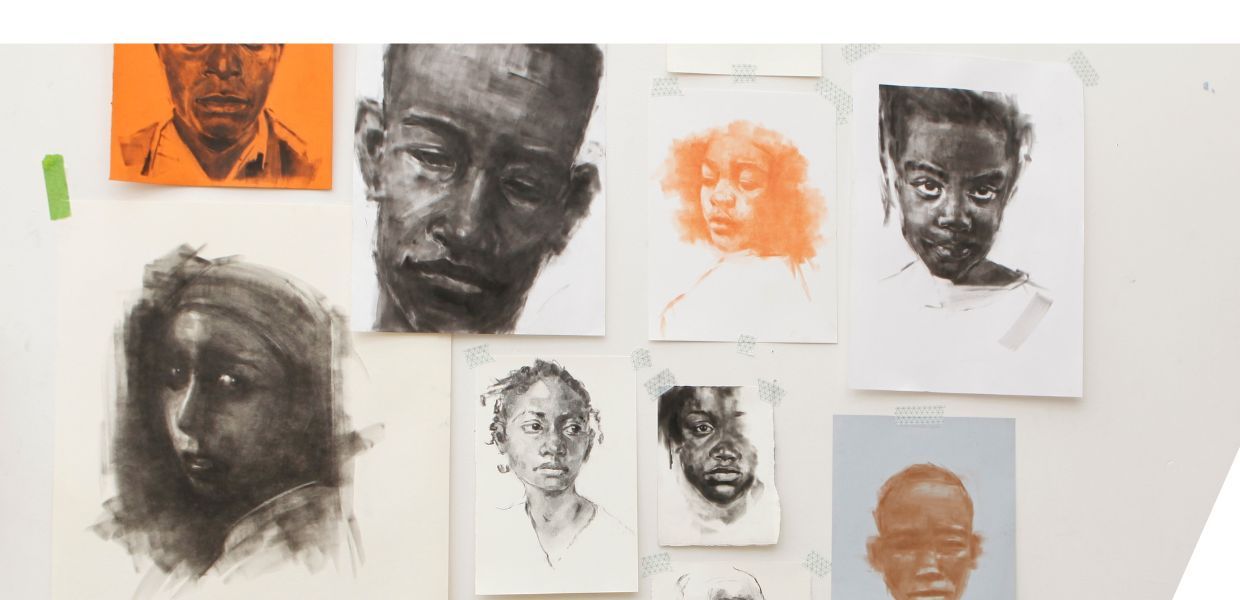 Drawings and paintings of faces hanging in an artist's studio