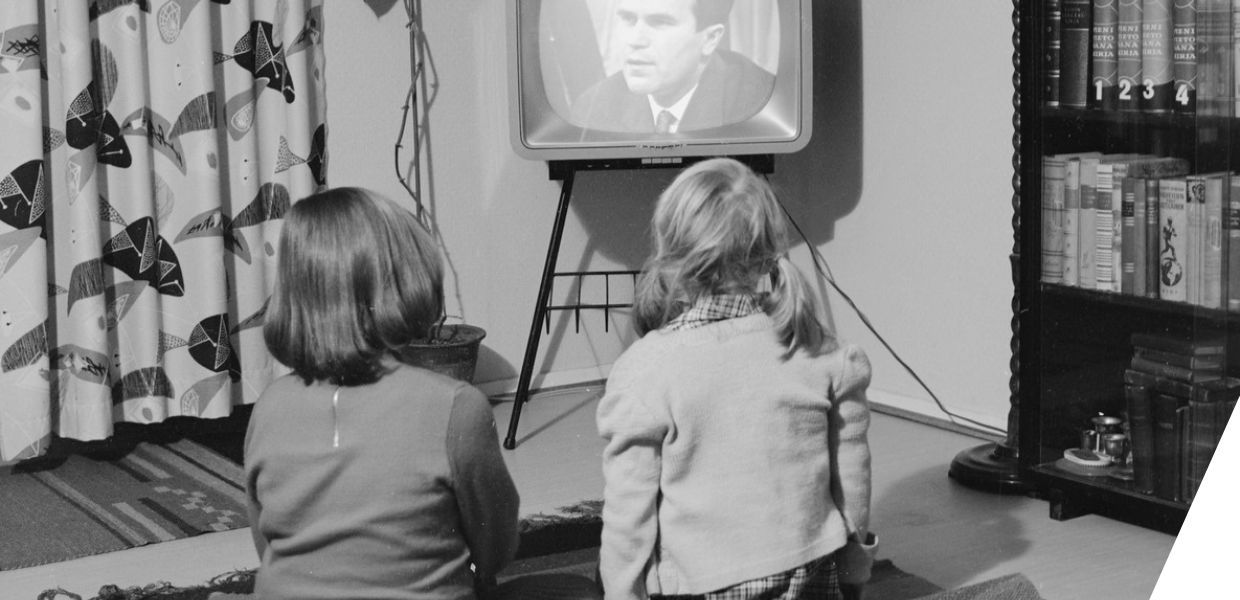 Two children sat on the floor watching TV