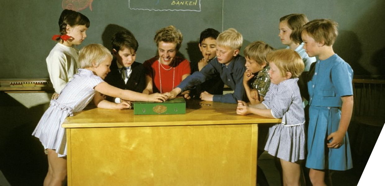 A group of children crowded round a desk in a classroom