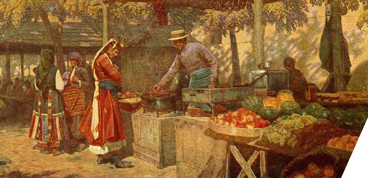 A vibrant outdoor market scene shows a man cooking and serving food under a rustic wooden stall, surrounded by fresh produce like apples, grapes, and melons. Women in traditional clothing stand nearby, engaged in conversation and examining the goods.