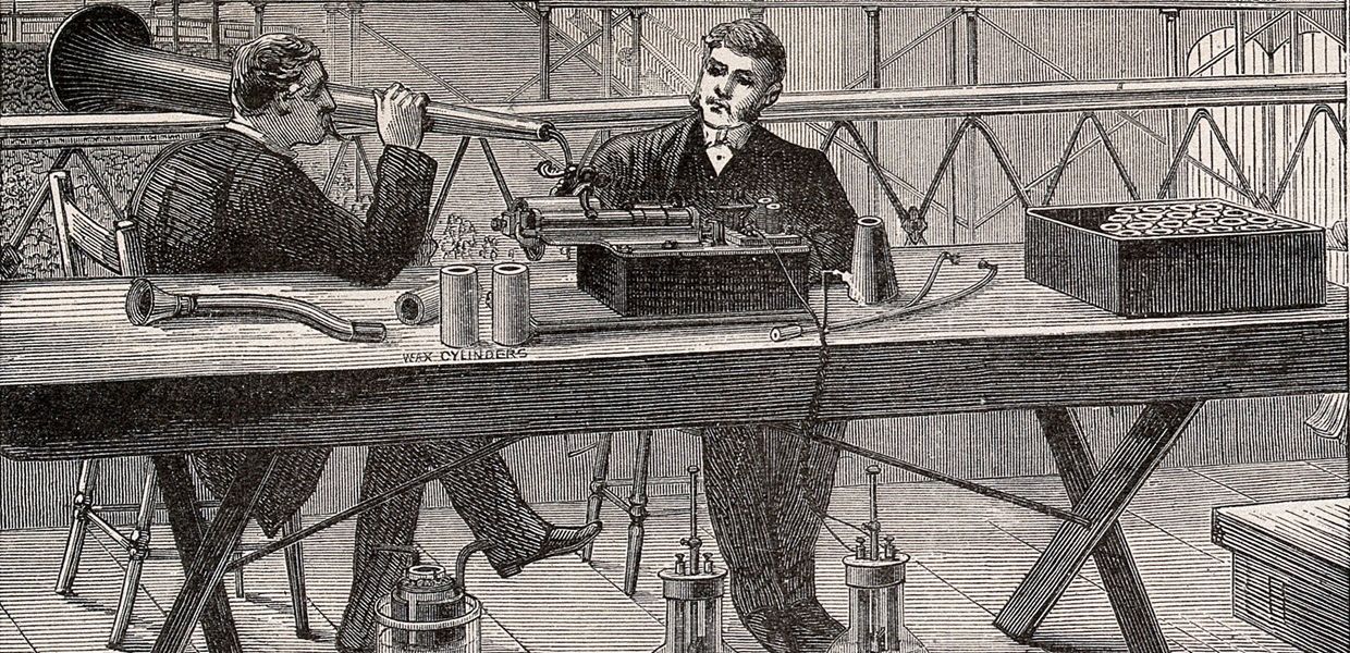 A wood engraving showing two men demonstrating the use of an electrically-powered Edison-type phonograph