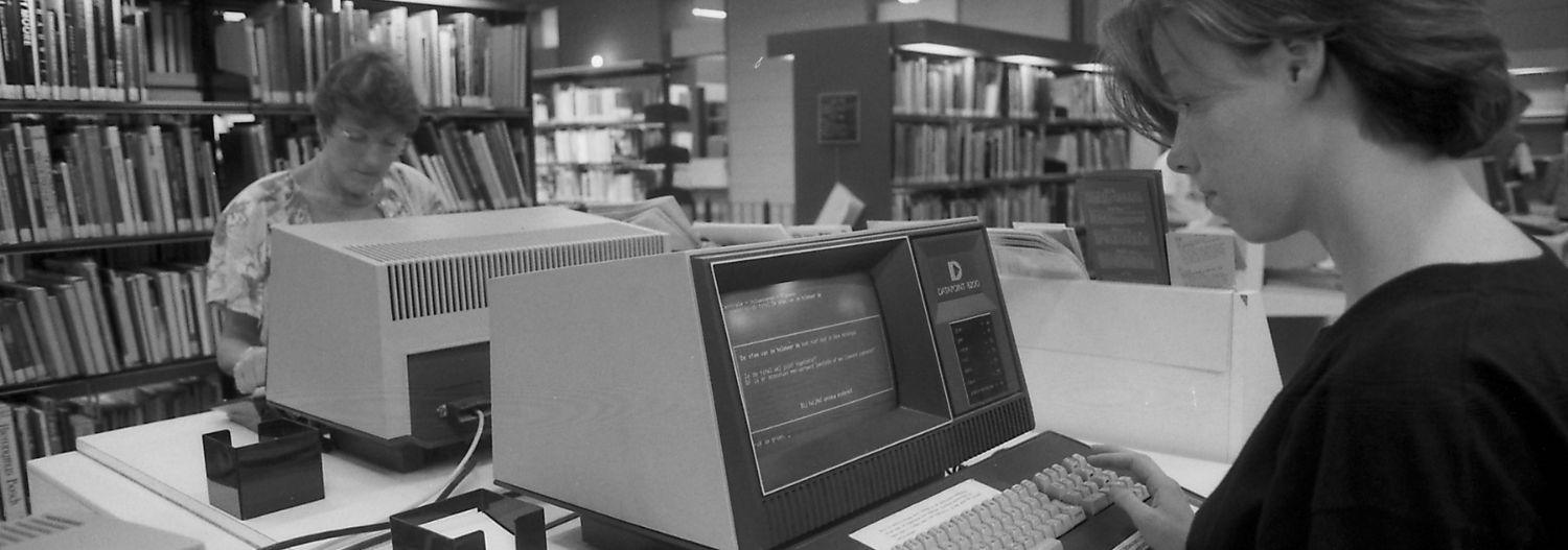 A person in a library looking at a computer screen